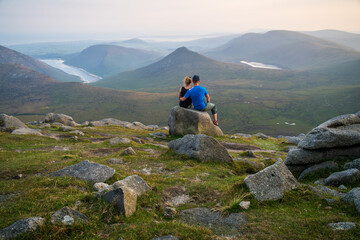 Couple sitting on the rock. Panoramic view of the Mourne Mountains, beautiful part of Northern Ireland