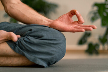 close-up of hands and fingers of man meditating in hall and sitting in lotus position man taking...