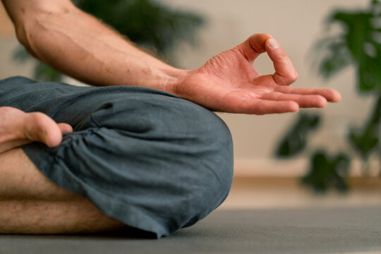 close-up of hands and fingers of man meditating in hall and sitting in lotus position man taking care of his mental health