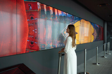Portrait of Asian Vietnamese woman with dress at Sky bar looking at TV screen in museum, urban city, Vietnam. People lifestyle.