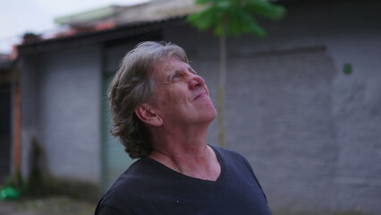One senior man gazing up at sky standing in urban street. Close-up face tracking shot in motion...
