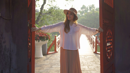 Portrait of Asian Vietnamese woman travel in The Red Bridge in public park garden with trees in Hoan Kiem Lake in Downtown Hanoi. Urban city, Vietnam..