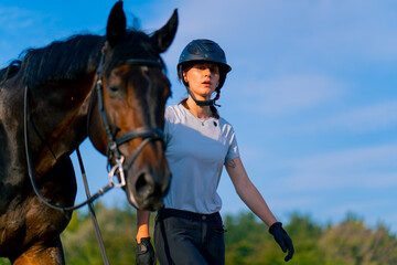 A helmeted rider leads her beautiful black horse by the harness in the riding arena during a...