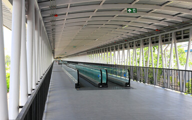 Pedestrian pathway or corridor or hallway with automatic walkway or Moving Sidewalk between train station and building.