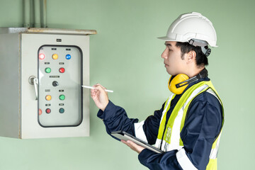 Building inspector man checking and pointing at air pressurized fan system control cabinet. Asian...