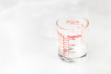 glass measuring cup or dosage cup with teaspoon measurements displayed.