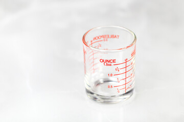 glass measuring cup or dosage cup with ounce measurements displayed.