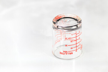 inverted glass measuring cup or dosage cup with milliliter measurements displayed.