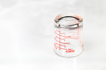 inverted glass measuring cup or dosage cup with ounce measurements displayed.