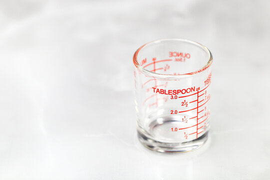glass measuring cup or dosage cup with tablespoon measurements displayed.