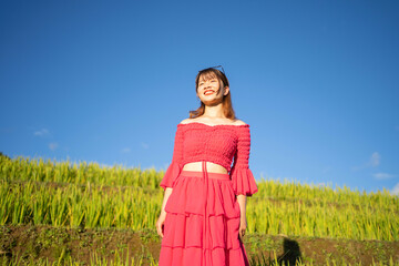 A farmer woman with fresh paddy rice terraces, green agricultural fields in countryside or rural area of Mu Cang Chai, mountain hills valley in Asia, Vietnam. Nature landscape. People lifestyle.