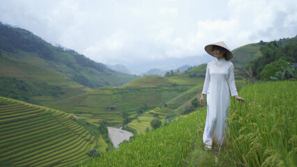Fototapeta na wymiar A farmer woman with fresh paddy rice terraces, green agricultural fields in countryside or rural area of Mu Cang Chai, mountain hills valley in Asia, Vietnam. Nature landscape. People lifestyle.