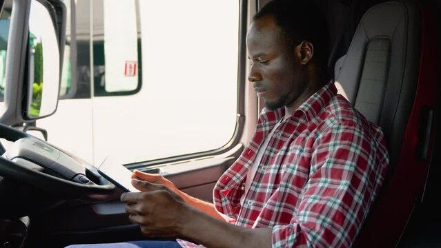 Professional african trucker using truck gps navigation to transport and deliver goods to the destination. Right hand drive car