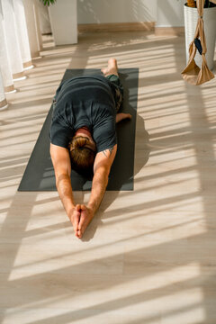 close-up of the arms and back of a man who is bent over at his feet doing a stretch hobby active lifestyle