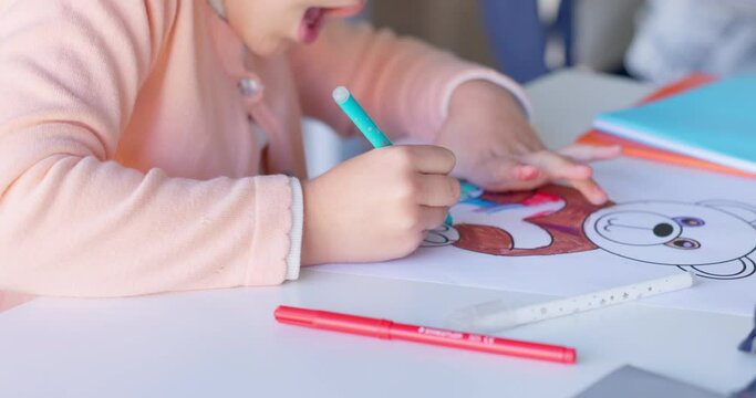 Girl child, drawing and color in classroom, learning and development with art, animal sketch or paper at desk. Female kid, writing and notebook for bear, education or pen for study, academy or school