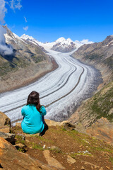 Young woman enjoying the stunning view of the Great Aletsch Glacier in Valais canton, Switzerland