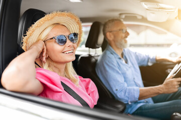 Happy senior man and woman going car trip together