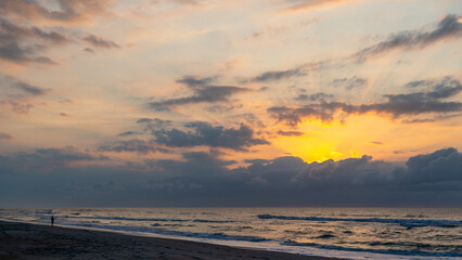 Fototapeta na wymiar Sun Rises behind the Clouds over the Sea