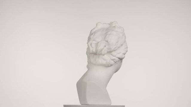 Closeup shot. Ancient marble bust statue of roman era woman spinning round on a platform. Isolated on white background. HDR BT2020 HLG Material.