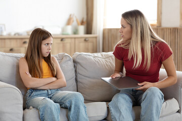 Strict mother scolding preteen daughter for long laptop use - obrazy, fototapety, plakaty