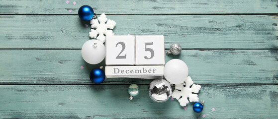 Christmas decorations and calendar with date DECEMBER, 25 on wooden background