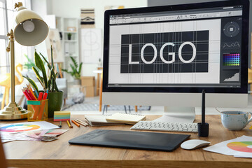 Graphic designer's workplace with computer, tablet and paint palettes in office