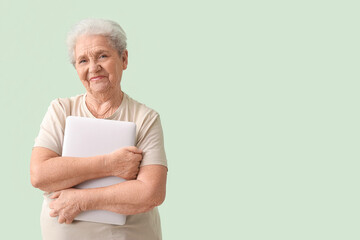 Senior woman with laptop on green background