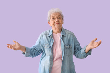 Confused senior woman on lilac background