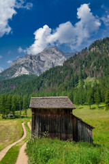Wooden hut next to road in a meadow in front of mountains, Fischleintal, South Tyrol, Trentino, Italy