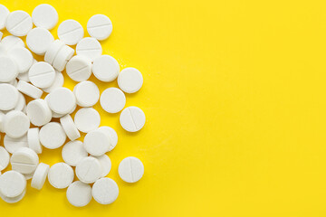 Heap of white pills on yellow background - obrazy, fototapety, plakaty