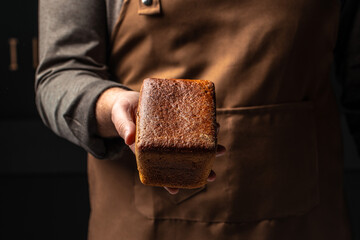 Small brown bread in hands, domestic cozy bakery pastry. Healthy food concept. place for text