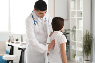 Doctor checking posture of little girl in clinic