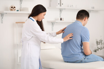 Fototapeta premium Female doctor checking posture of young man in clinic