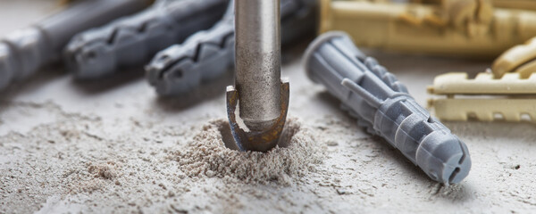 metal drill bit make holes in concrete wall on industrial drilling machine with shavings. Metal...