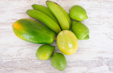 Different fresh green fruits on wooden background, papaya, banana, lime, passion fruit