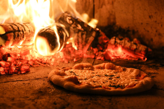 Pizza assando em forno a lenha.