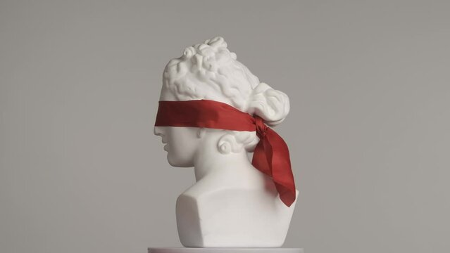 Closeup shot. Ancient marble bust statue of roman era woman blindfolded spinning on a platform. Isolated on grey background. HDR BT2020 HLG Material.