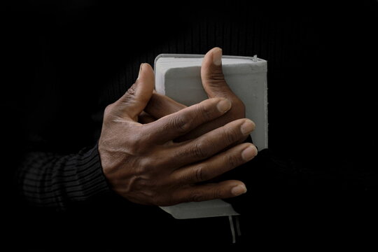 man praying with bible with black background with people stock image stock photo	