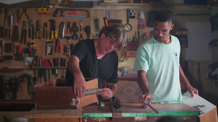 Carpentry Workshop of Master Carpenter and Apprentice Measuring Wood with Ruler, Engaged in Furniture Building and Repair Process