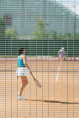 Girl girl playing tennis on court, sunny day. Blurred sport background