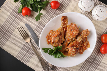 Baked chicken drumsticks with vegetables, spices and parsley on white plate, Top view