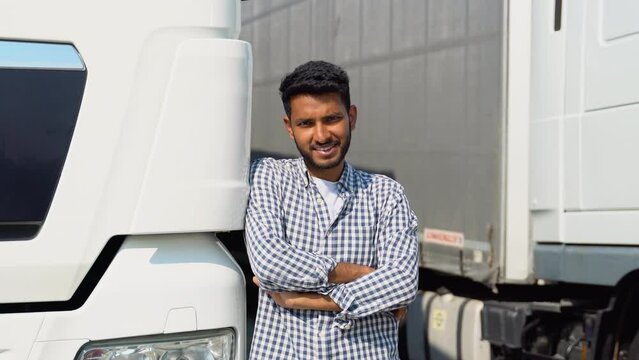 Positive indian asian truck driver in casual clothes with crossed arms standing by his truck
