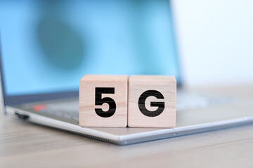 5G word on block cubes with laptop, network or communication idea, random wooden block cubes with...