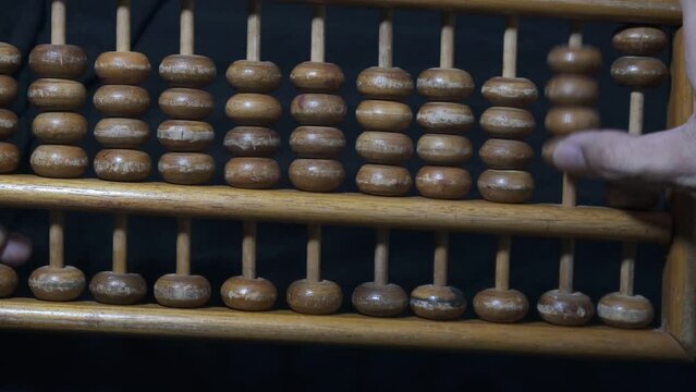 Male hand counting money using old wooden abacus with old paper with mathematical calculations and metal coins on the table close up. 4K footage