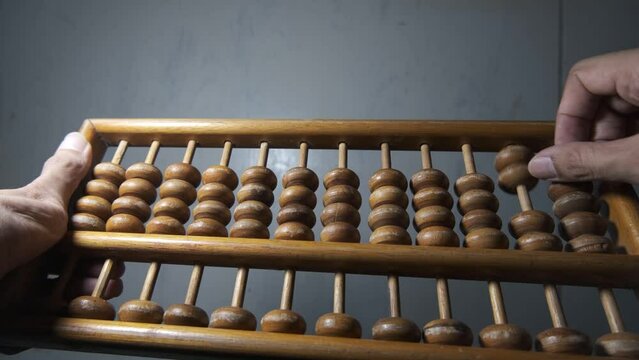 abacus. sempoa. Made of wood. An Asian man's hand is focused on counting. to calculate some simple addition equations. 4K footage.