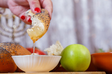 A woman's hand dips a piece of challah in honey on the Jewish holiday of Rosh Hashanah.