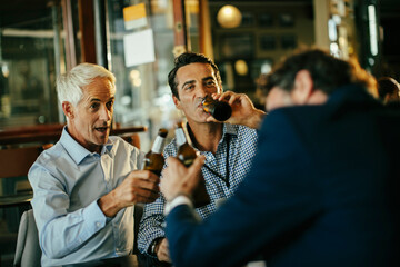 Diverse group of male businessman having a beer and celebrating closing a deal on their job