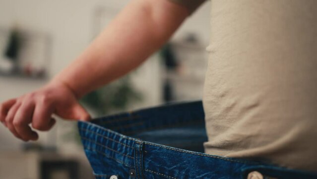 Closeup of man wearing big pants, great dieting results, successful weight loss