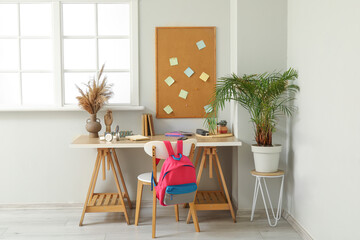 Modern school desk with stationery in room near white wall