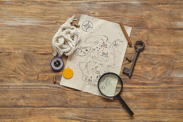 Treasure map with pirate amulet  and travel equipment on brown wooden background